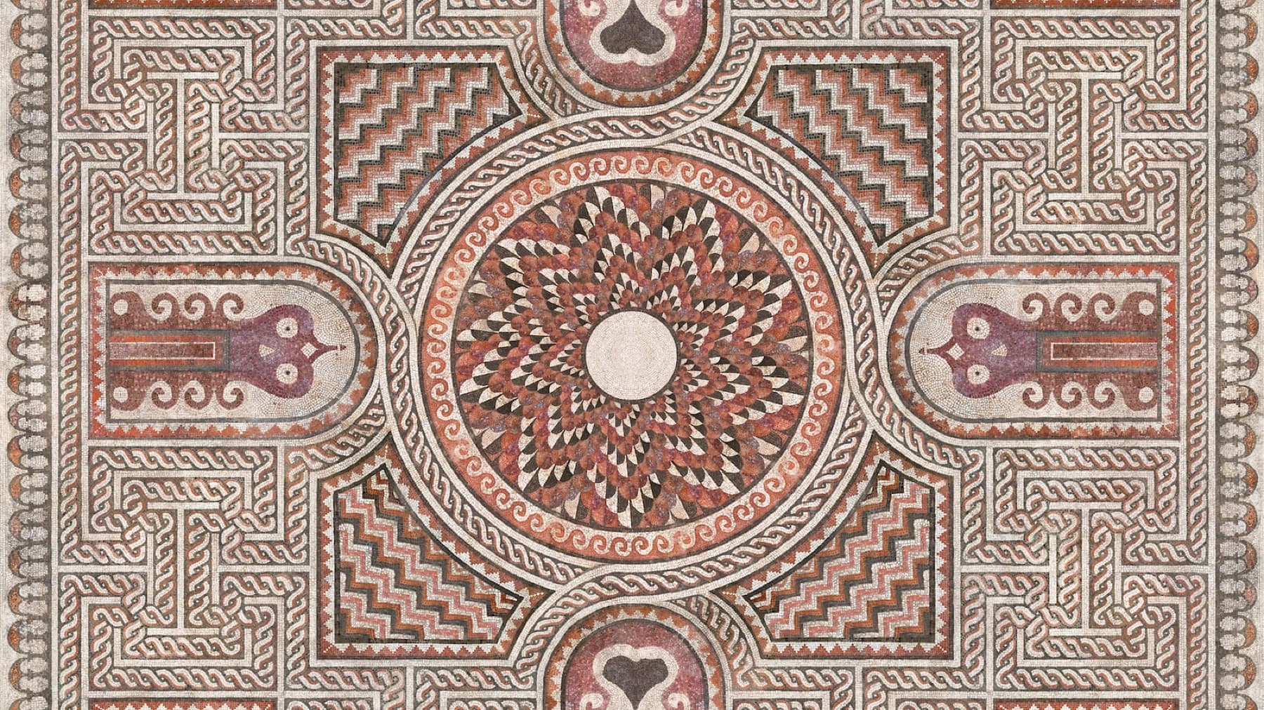 The Roman floor mosaic of Tirana: a central rosette medallion framed by interlocking geometric and floral motifs in natural stone colours.